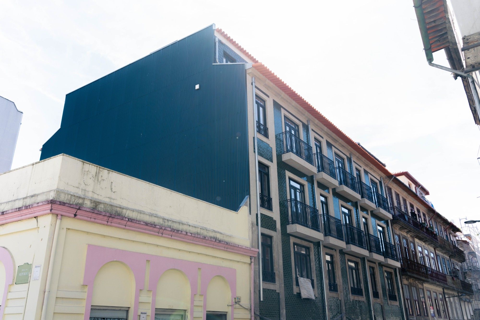 Edifício com fachada azul-escura e azulejos verdes, em rua urbana